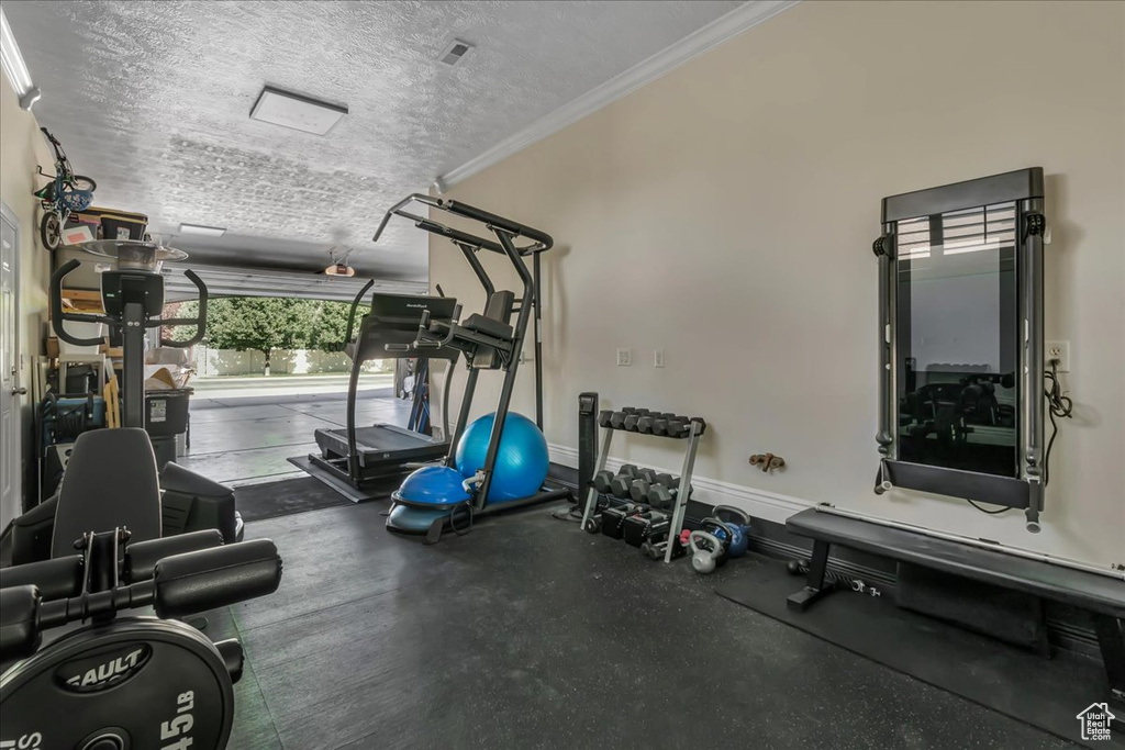 Exercise area featuring ornamental molding, a textured ceiling, and baseboards