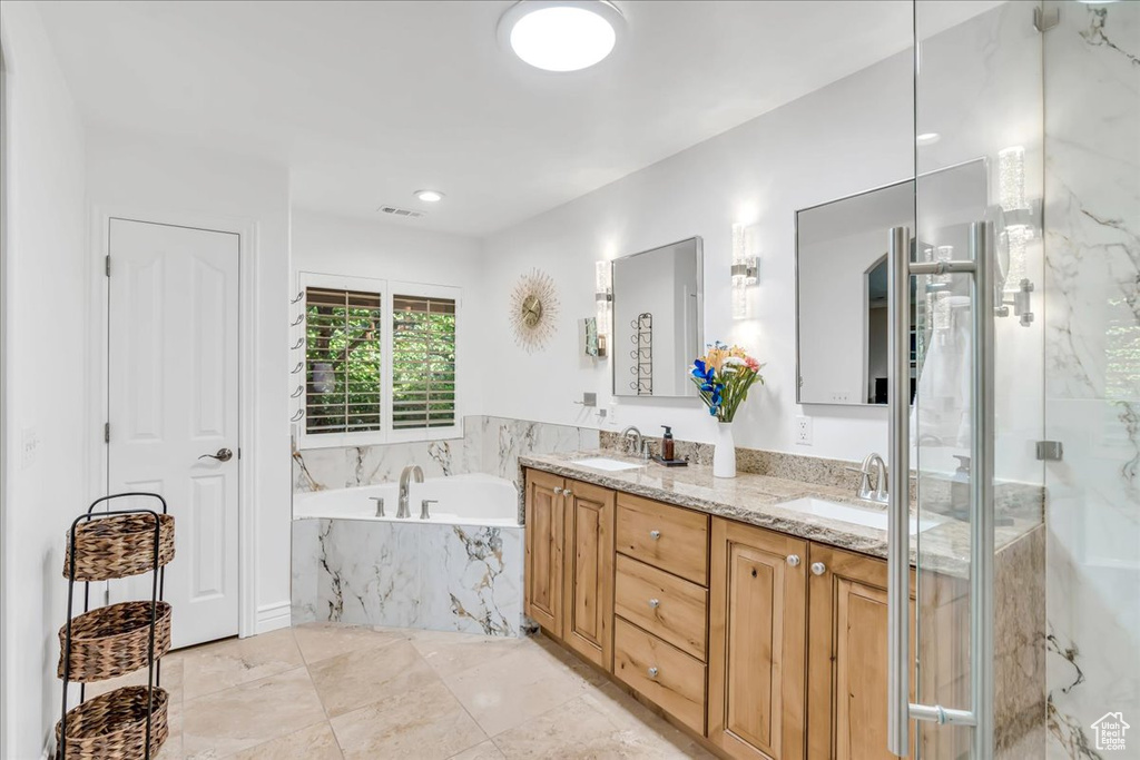 Full bath with a garden tub, double vanity, and a marble finish shower