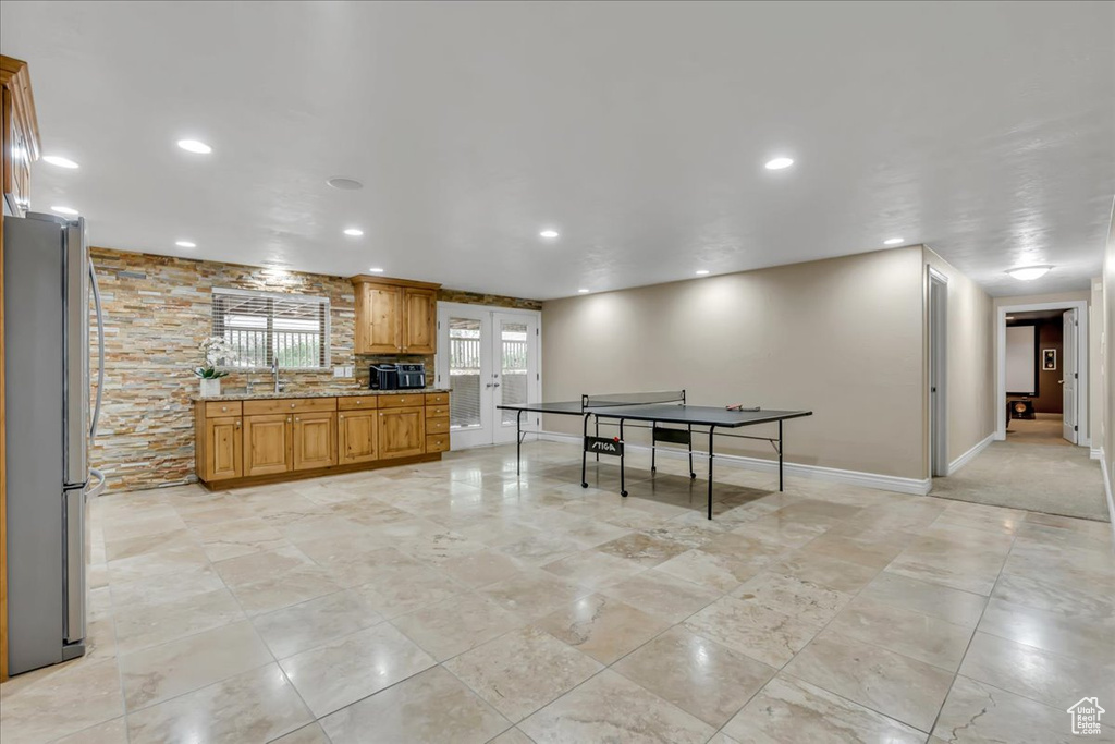 Kitchen with freestanding refrigerator, light stone countertops, recessed lighting, baseboards, and a sink