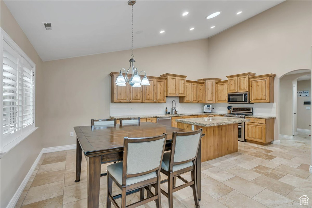 Kitchen with appliances with stainless steel finishes, baseboards, high vaulted ceiling, a sink, and arched walkways
