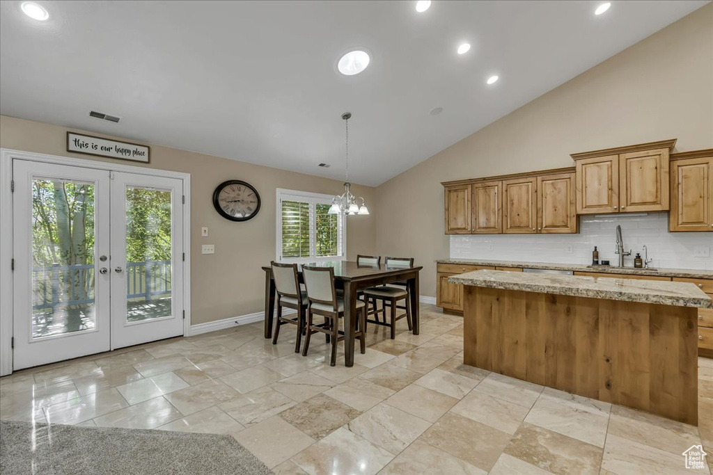 Kitchen with a sink, decorative backsplash, a kitchen island, baseboards, and recessed lighting
