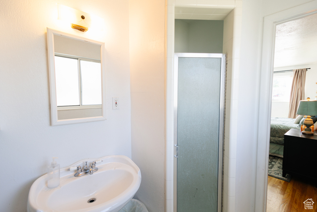 Ensuite bathroom featuring a sink, a stall shower, and wood finished floors