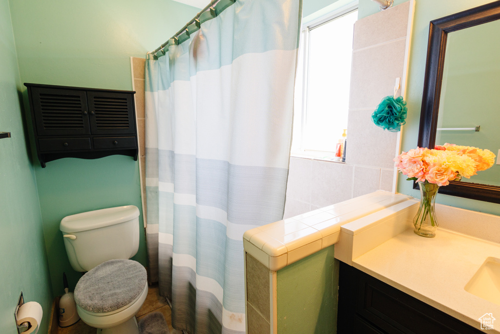 Bathroom featuring healthy amount of natural light, vanity, toilet, and a shower with shower curtain