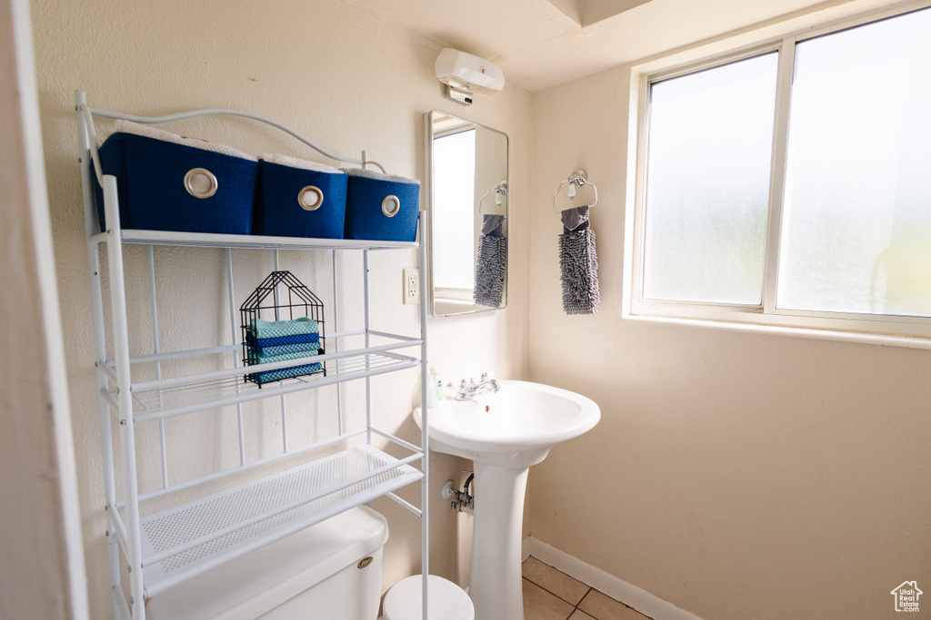 Half bathroom featuring toilet, tile patterned flooring, and baseboards