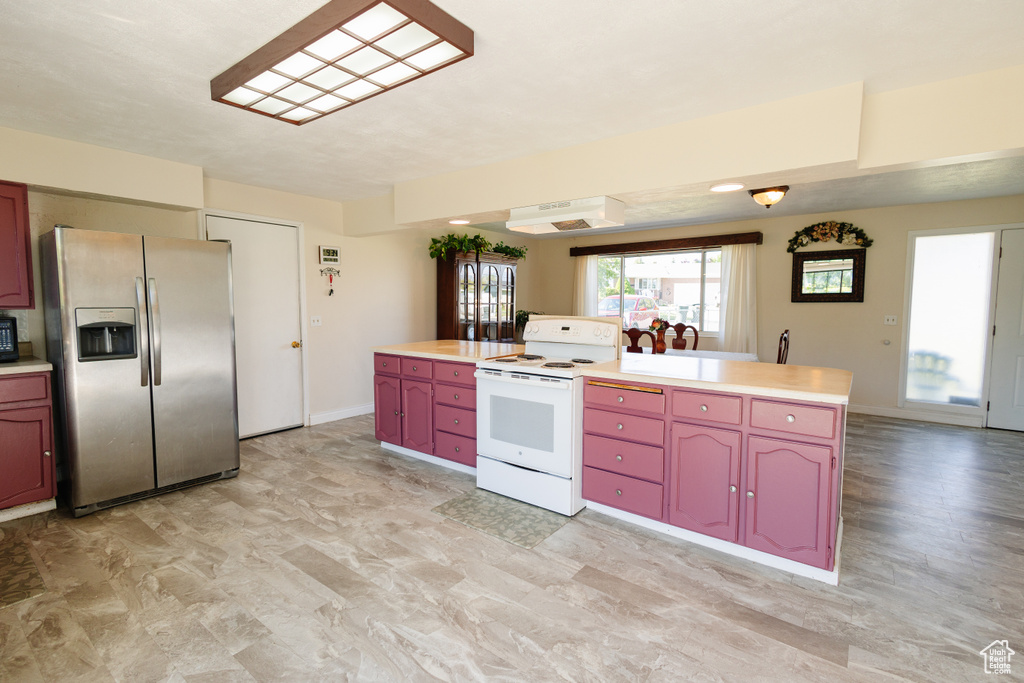 Kitchen featuring stainless steel fridge with ice dispenser, electric stove, light countertops, and baseboards