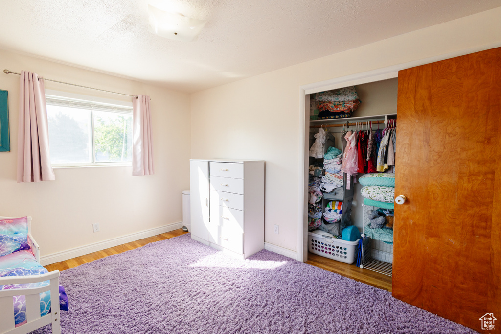 Bedroom with a closet, wood finished floors, and baseboards