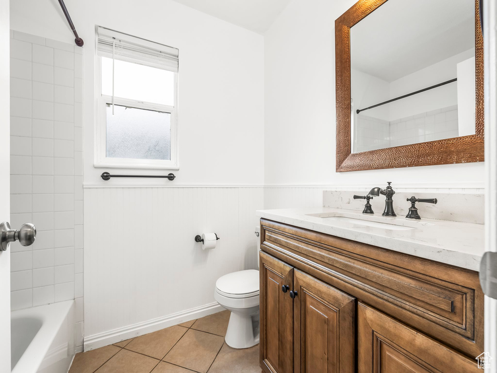Bathroom featuring vanity, toilet, a wainscoted wall, tile patterned flooring, and  shower combination