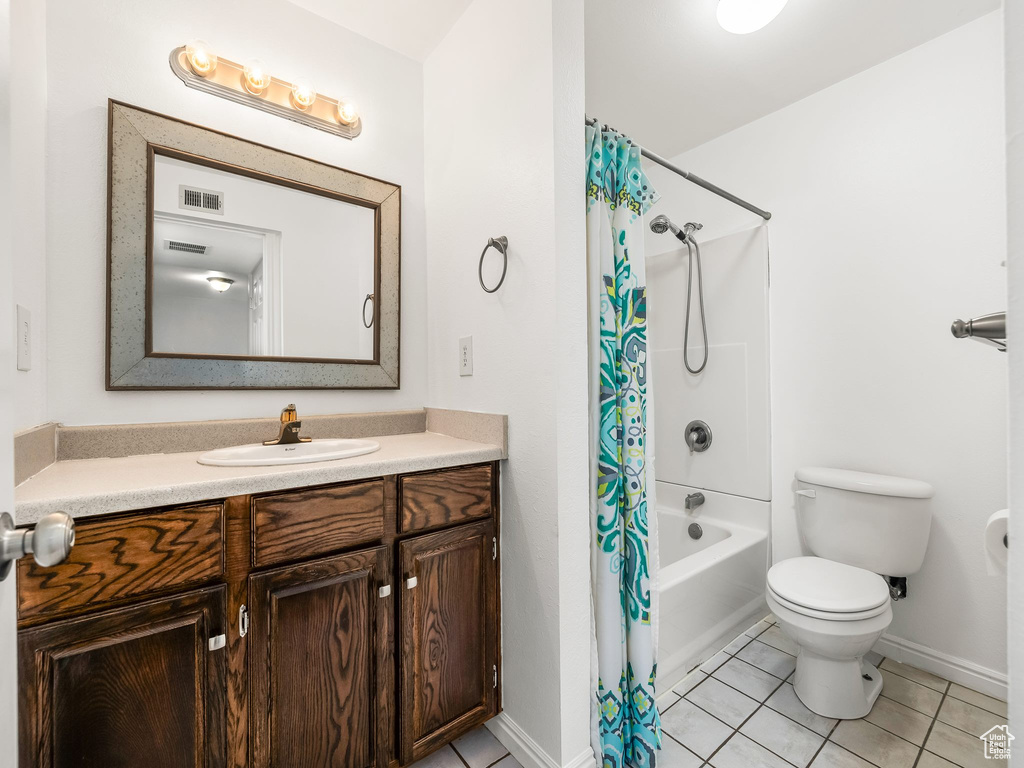 Full bath with vanity, tile patterned floors, shower / bath combination with curtain, baseboards, and toilet