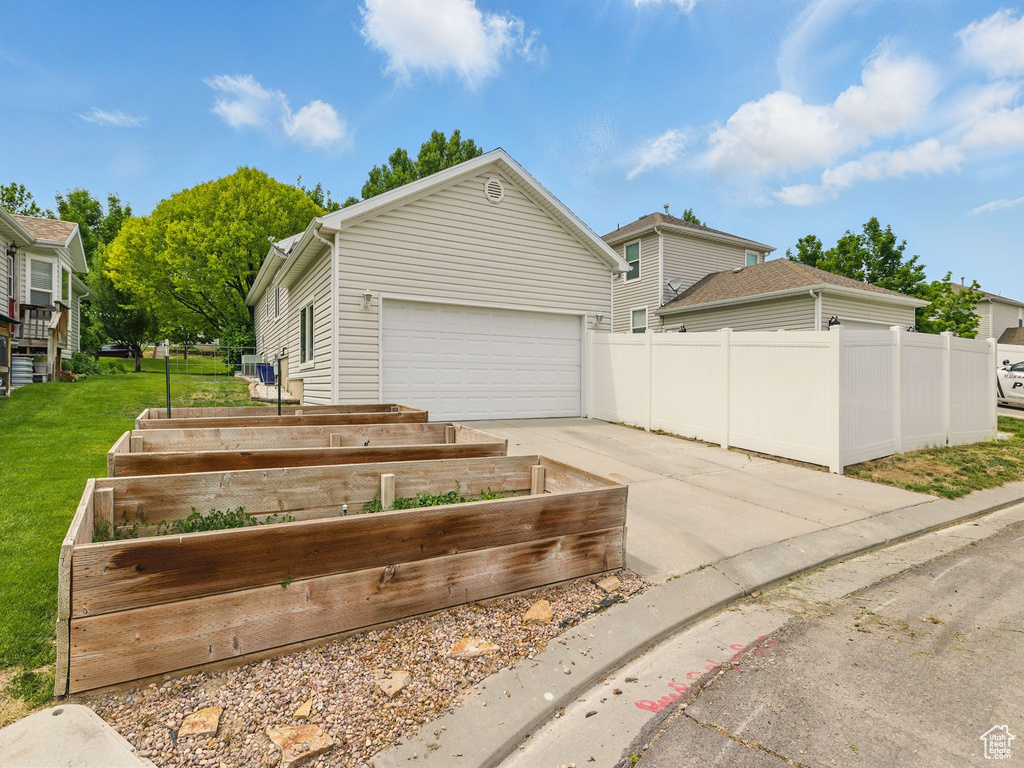 View of front of house featuring a vegetable garden, concrete driveway, and a garage