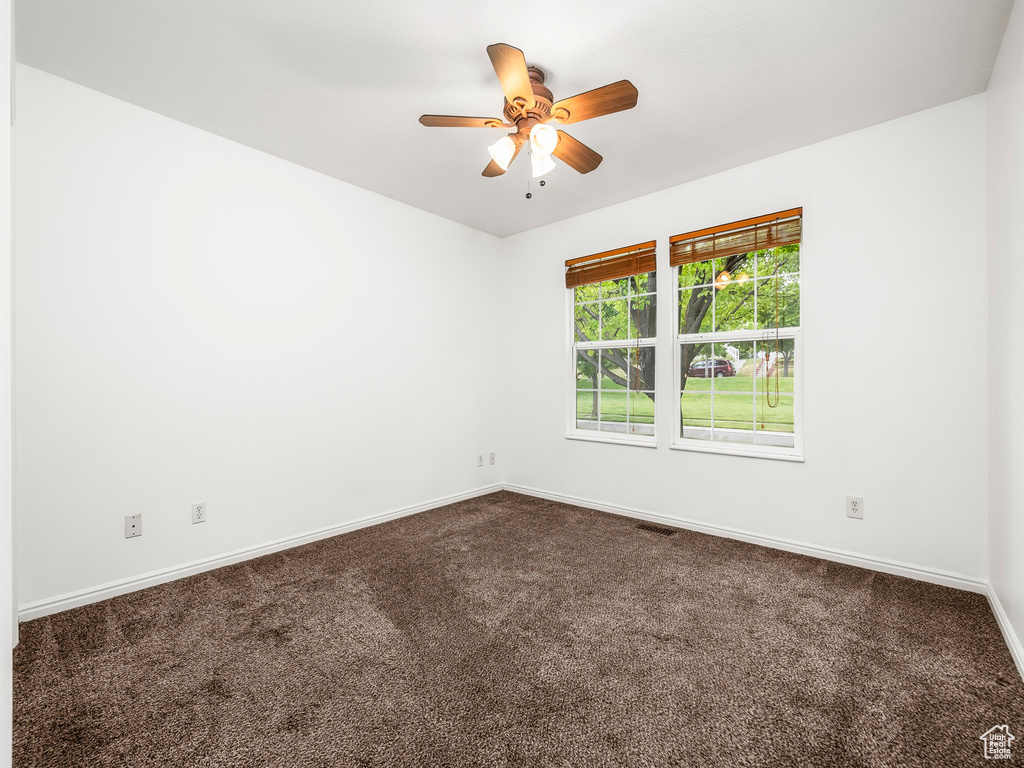 Empty room with baseboards, ceiling fan, and dark colored carpet