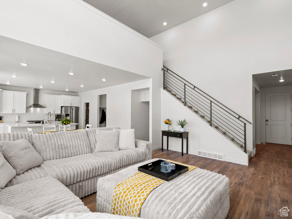 Living room featuring stairs, recessed lighting, dark wood-style floors, and baseboards