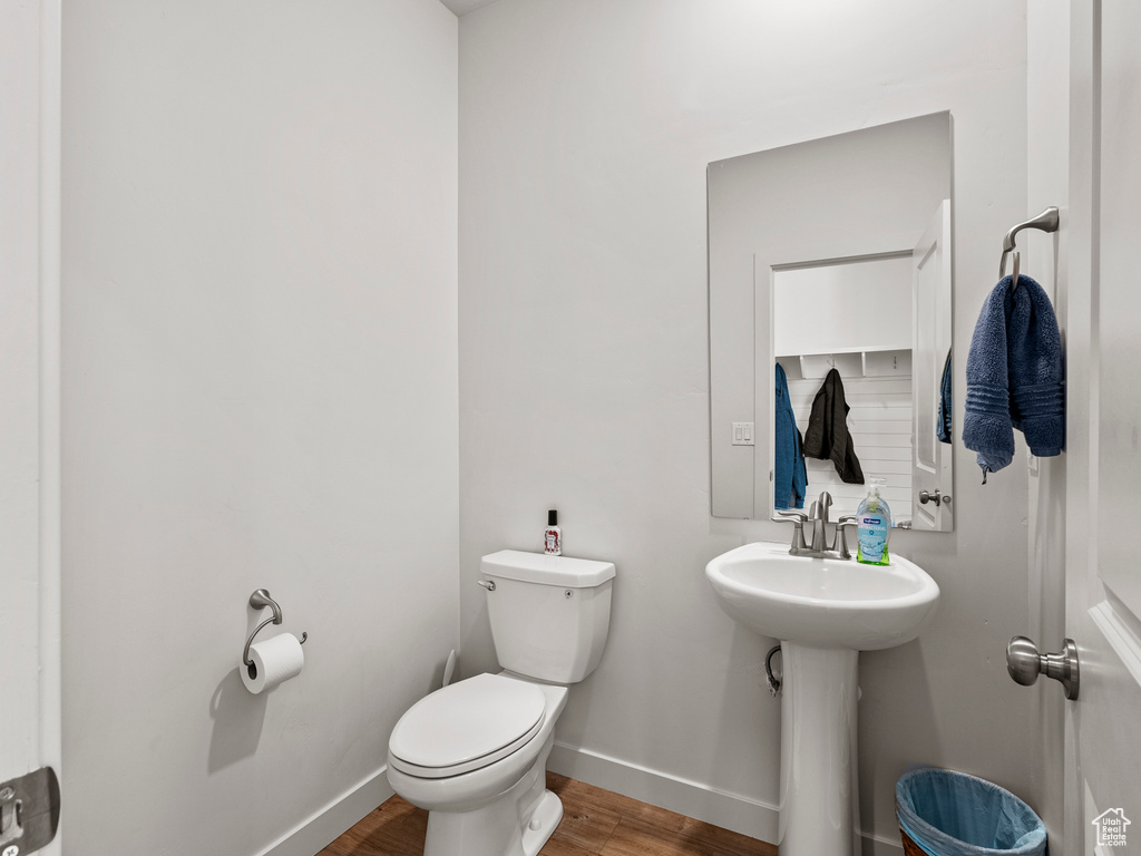 Bathroom with wood finished floors, toilet, baseboards, and a sink