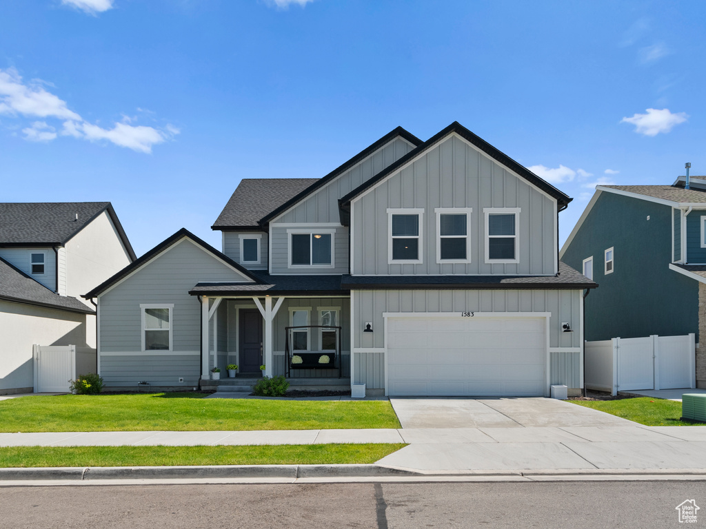 View of front facade with board and batten siding, concrete driveway, an attached garage, and roof with shingles