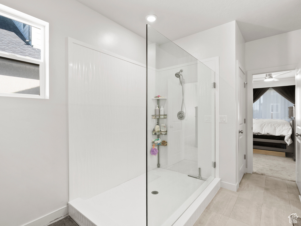 Bathroom featuring connected bathroom, walk in shower, a ceiling fan, and baseboards
