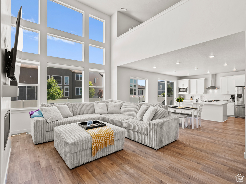 Living area featuring light wood-style floors, recessed lighting, and a high ceiling