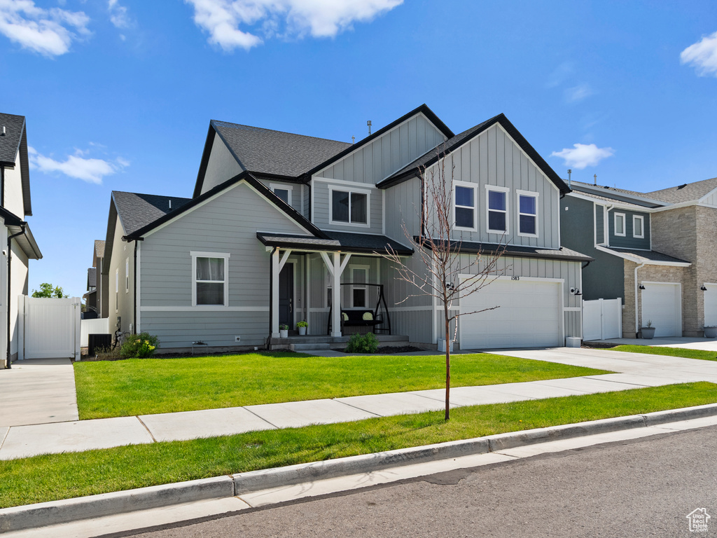 View of front of property featuring board and batten siding, driveway, a garage, a gate, and roof with shingles