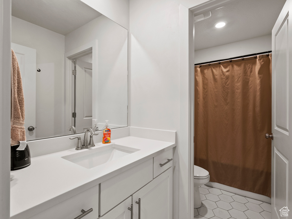 Bathroom featuring vanity, toilet, a shower with curtain, and tile patterned flooring
