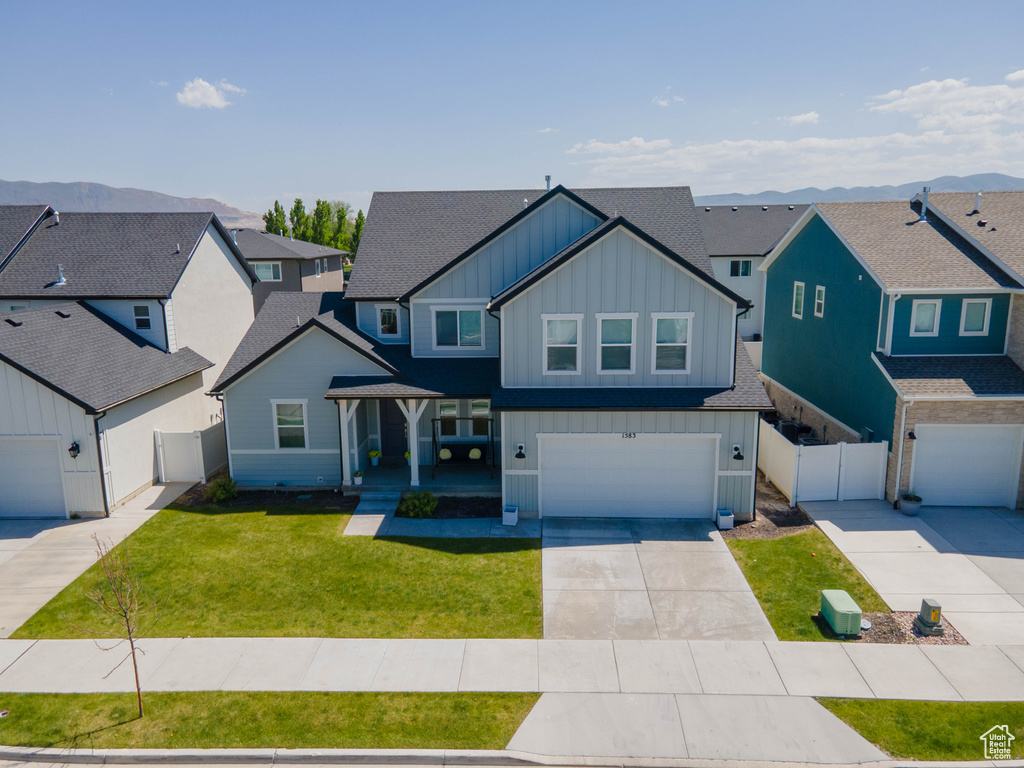 View of front of home with board and batten siding, a residential view, driveway, and a garage