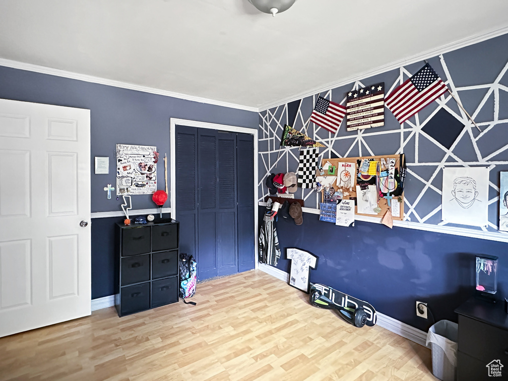 Bedroom with a closet, wood finished floors, baseboards, and crown molding