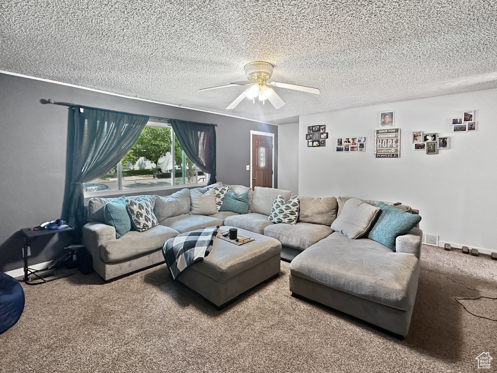 Living room with carpet floors, a textured ceiling, and a ceiling fan