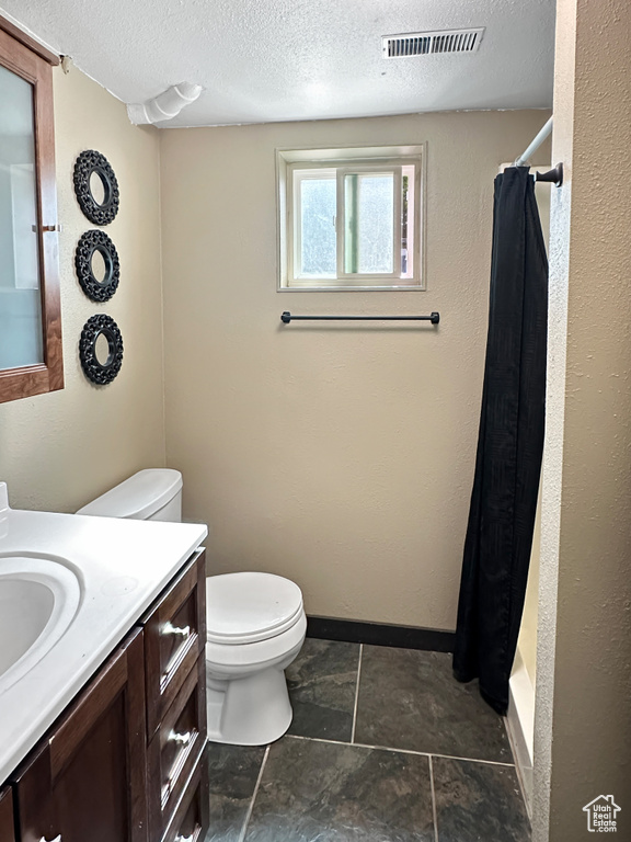 Full bath featuring toilet, vanity, a shower with curtain, a textured ceiling, and baseboards