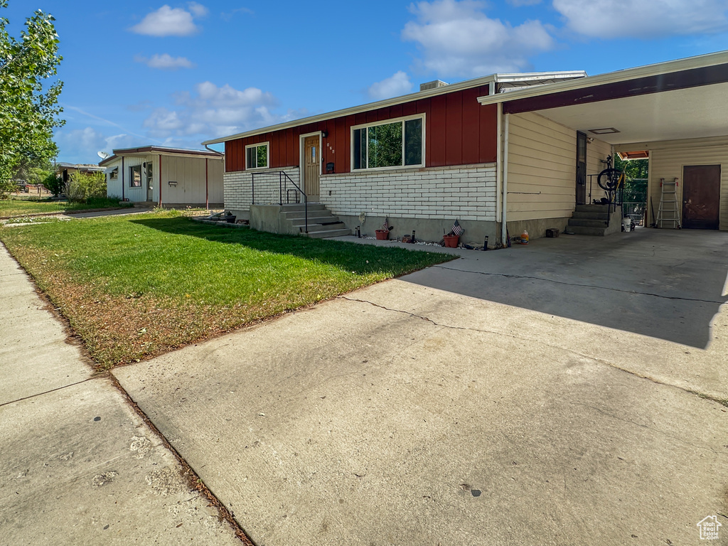 View of front of property with concrete driveway, a front yard, and an attached carport