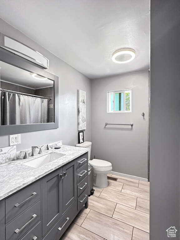 Full bathroom with vanity, toilet, and baseboards