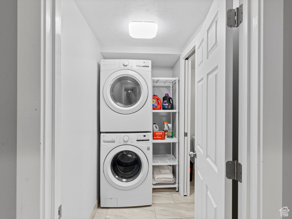 Washroom featuring stacked washing machine and dryer and a textured ceiling