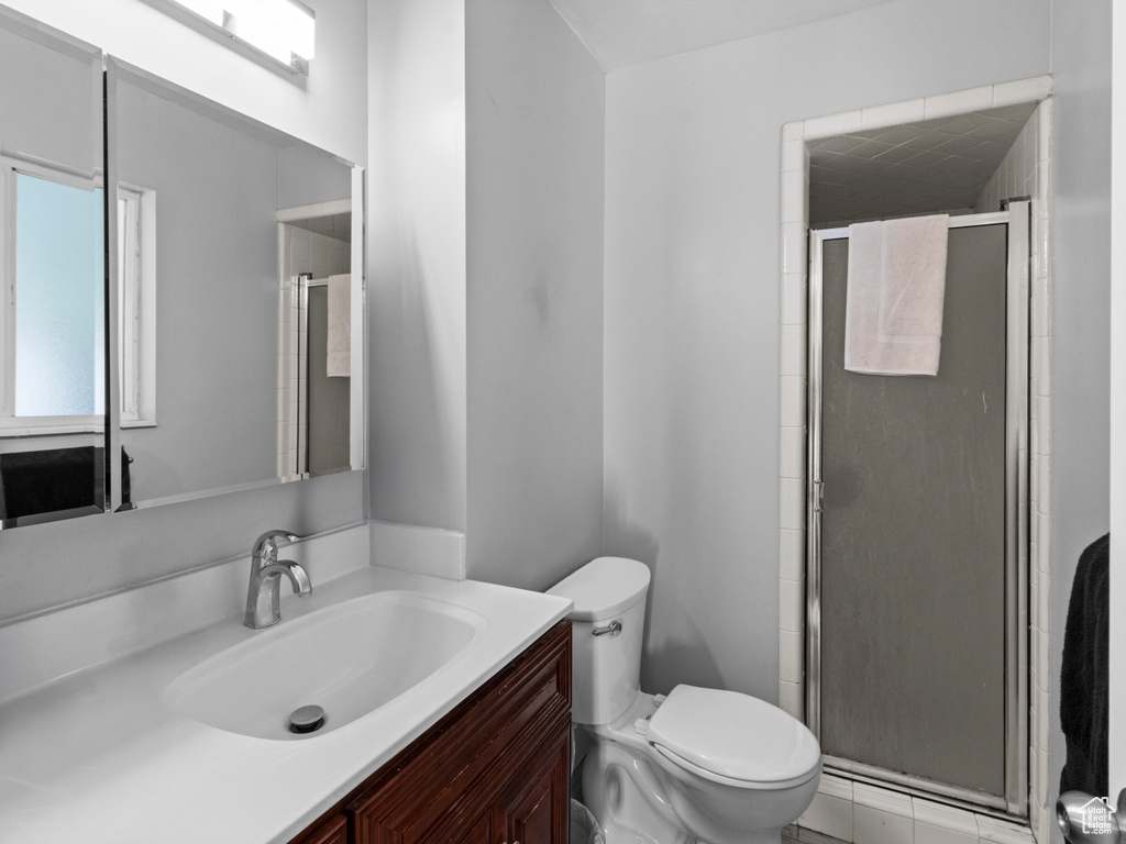 Bathroom featuring vanity, toilet, and a stall shower