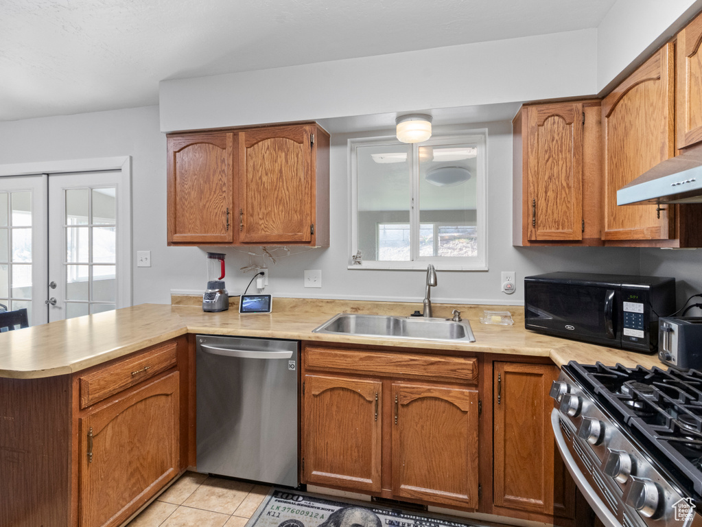 Kitchen featuring stainless steel appliances, a sink, a peninsula, and light countertops