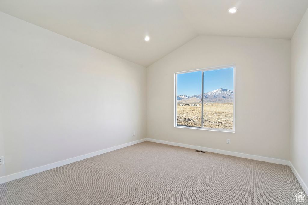 Spare room featuring light carpet, lofted ceiling, baseboards, recessed lighting, and a mountain view