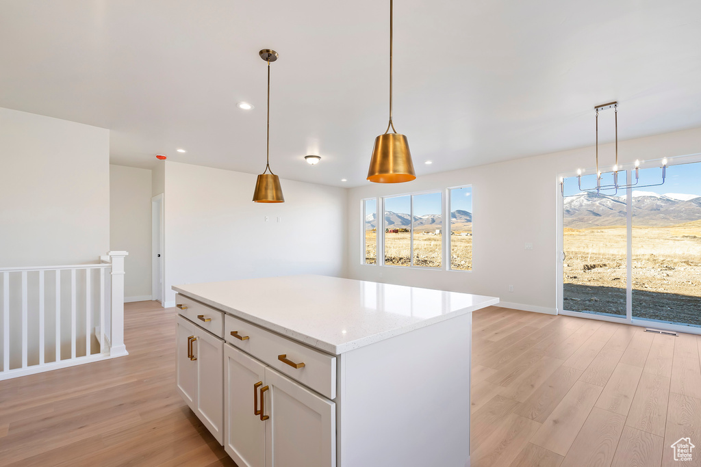 Kitchen with light wood finished floors, plenty of natural light, a kitchen island, decorative light fixtures, and recessed lighting