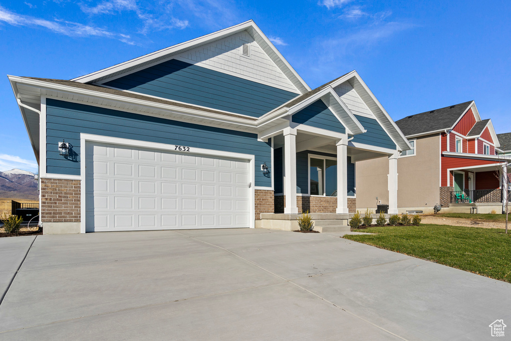 Craftsman-style home with covered porch, concrete driveway, brick siding, and a garage