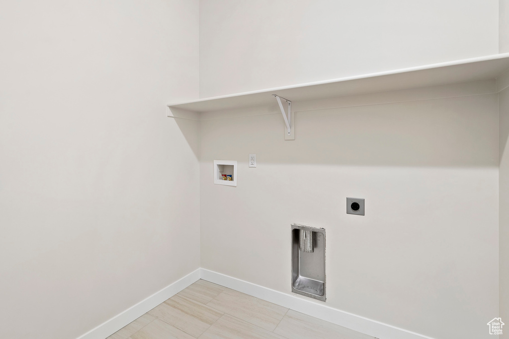 Washroom with electric dryer hookup, hookup for a washing machine, and baseboards