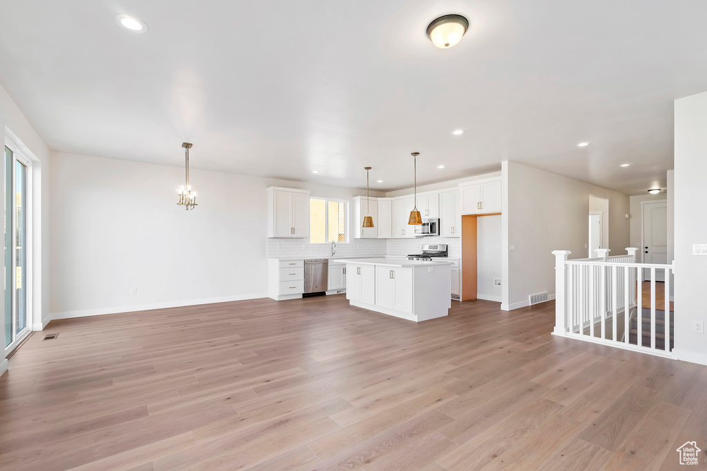 Unfurnished living room with recessed lighting, light wood finished floors, baseboards, and a chandelier