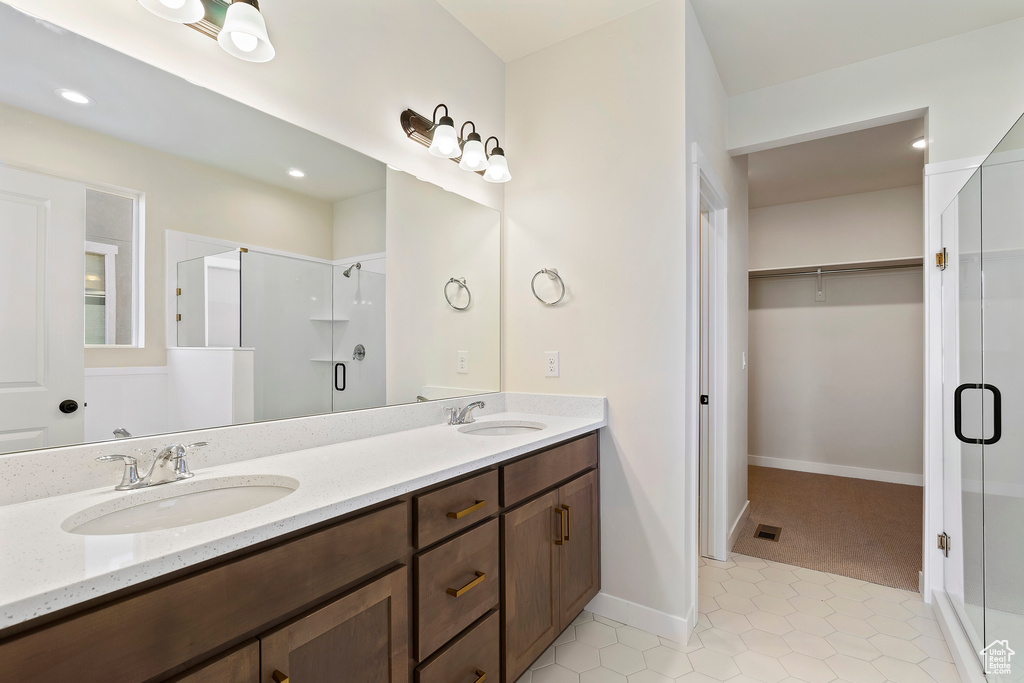 Bathroom featuring a stall shower, double vanity, a spacious closet, tile patterned floors, and recessed lighting