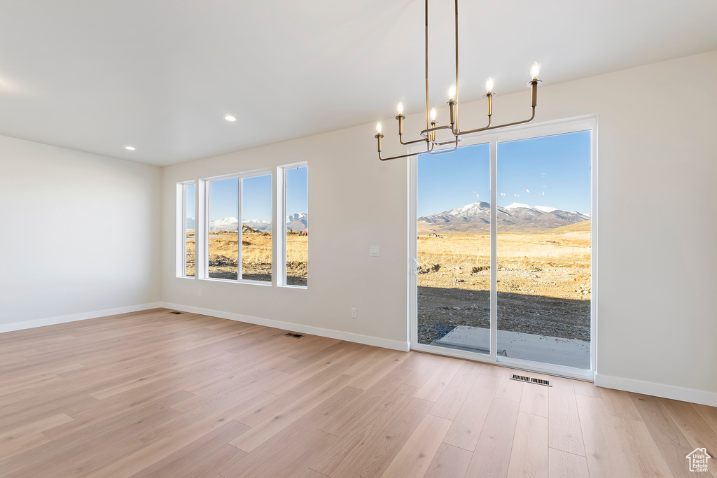 Unfurnished dining area featuring light wood-style flooring, a chandelier, a mountain view, recessed lighting, and baseboards
