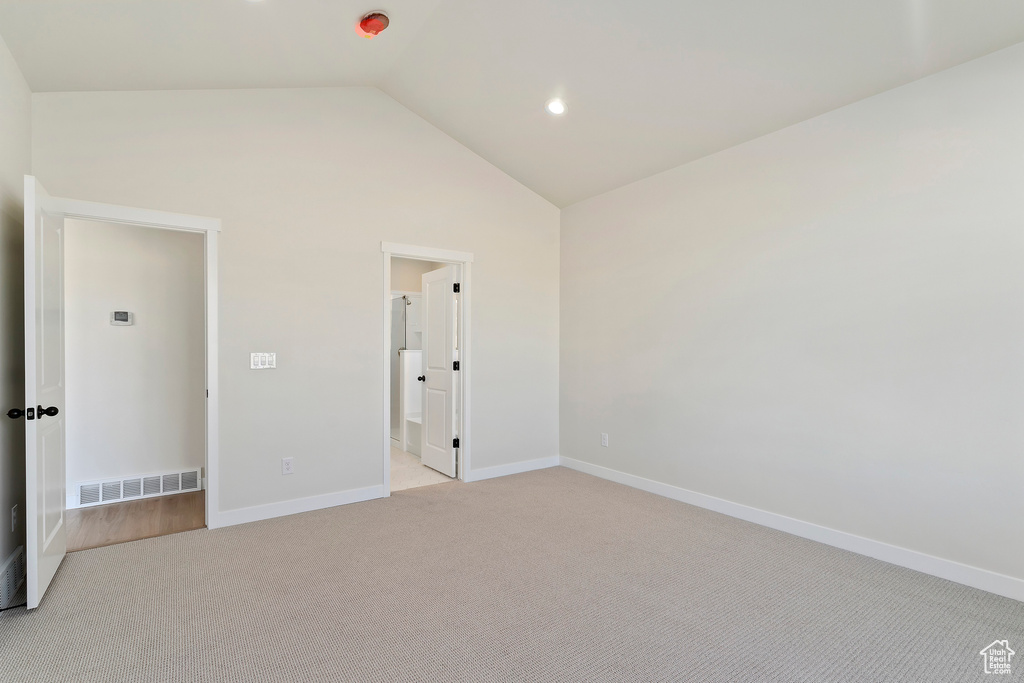 Unfurnished bedroom featuring light carpet, lofted ceiling, baseboards, and recessed lighting
