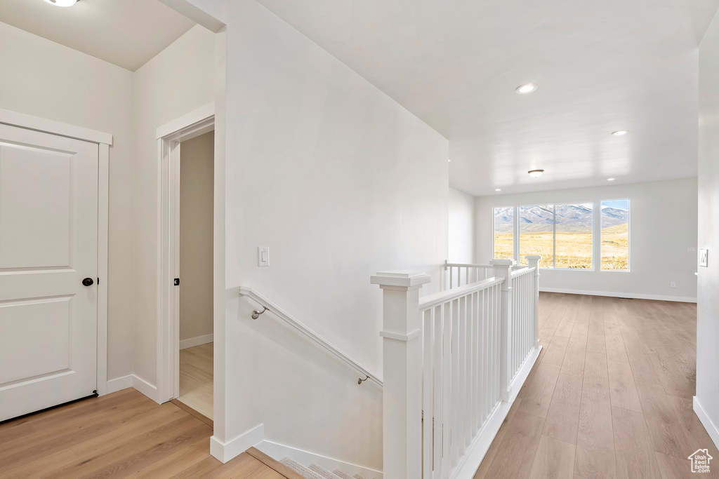 Corridor featuring an upstairs landing, light wood finished floors, baseboards, and recessed lighting