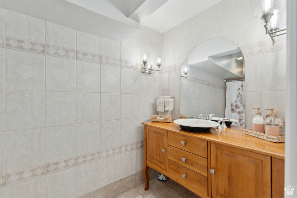 Bathroom featuring tile walls, tile patterned floors, vanity, and curtained shower