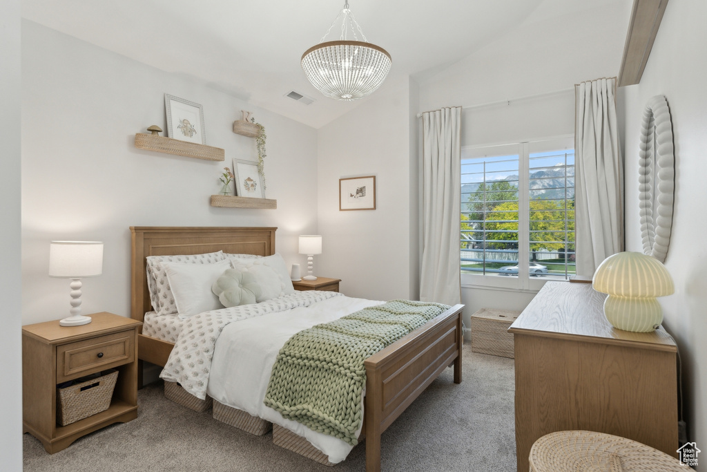 Bedroom featuring carpet floors, vaulted ceiling, and a chandelier