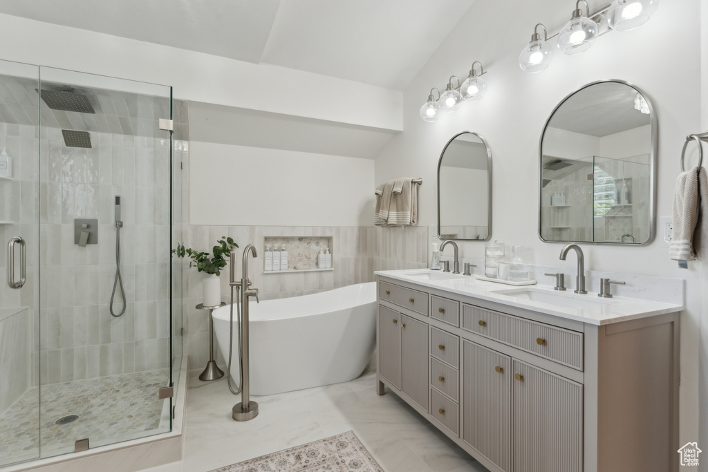 Bathroom featuring a shower stall, double vanity, a soaking tub, and marble look tile flooring