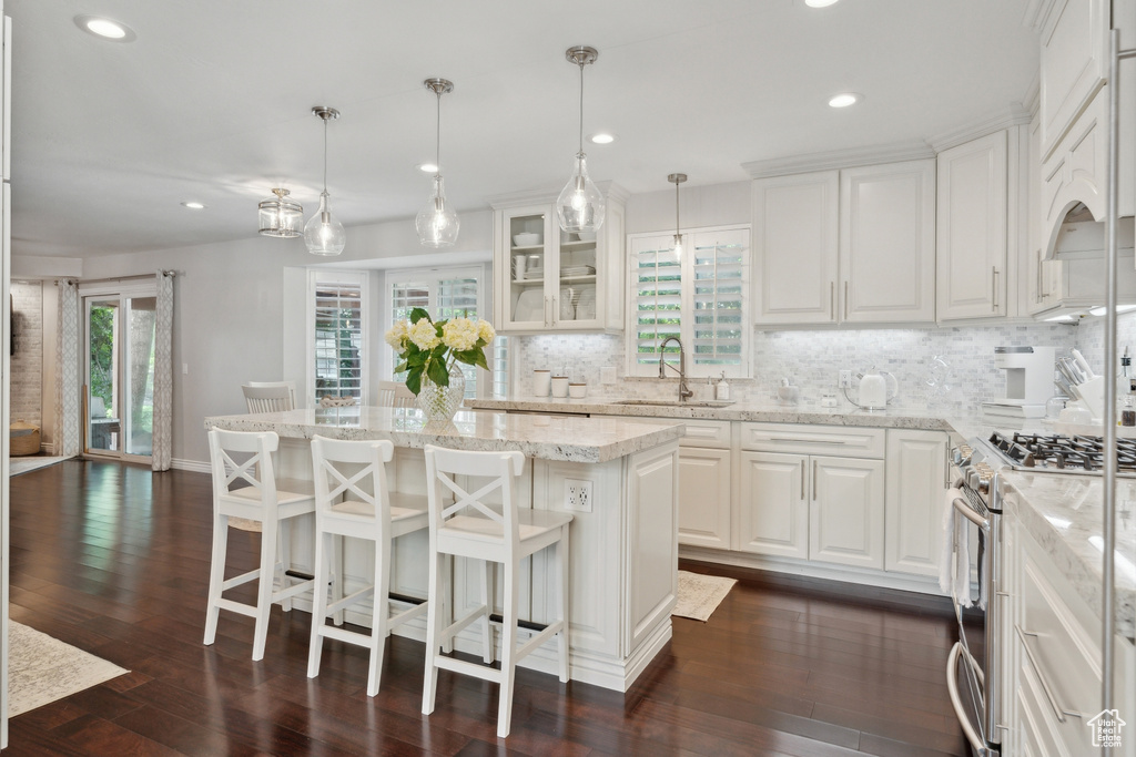 Kitchen with a sink, gas stove, recessed lighting, tasteful backsplash, and white cabinetry