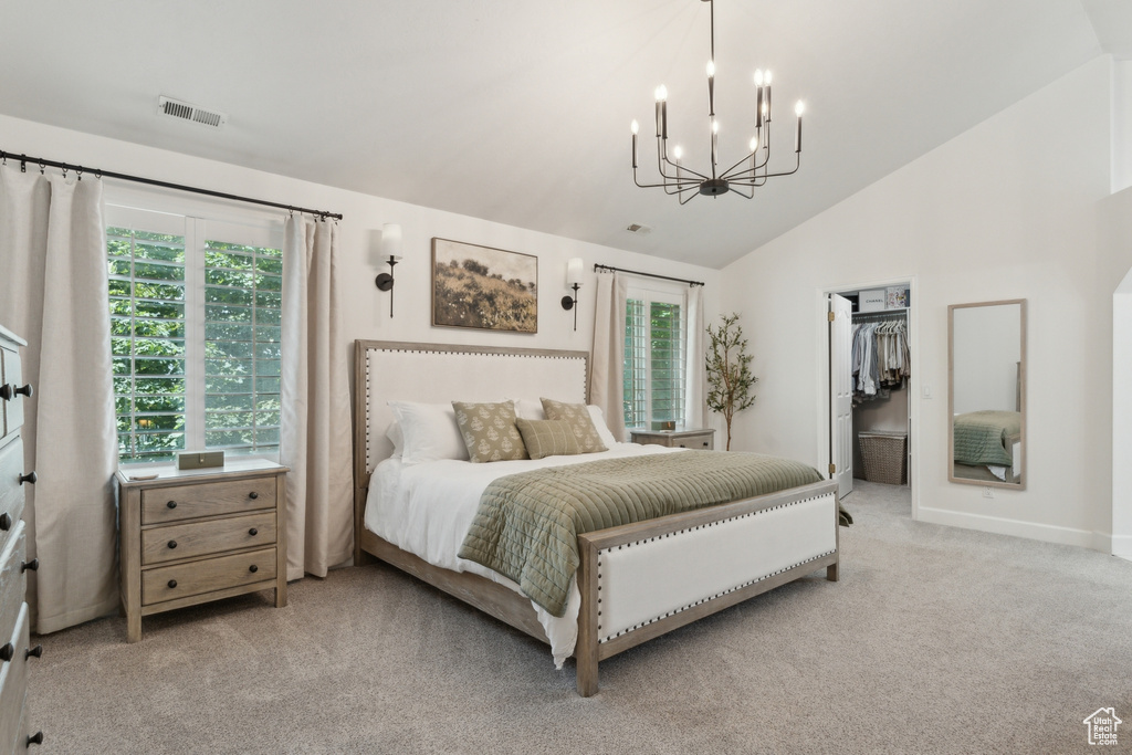 Carpeted bedroom with lofted ceiling, a chandelier, multiple windows, baseboards, and a walk in closet
