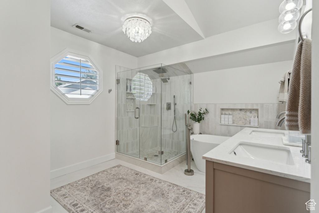 Full bathroom with a soaking tub, a shower stall, a chandelier, and double vanity