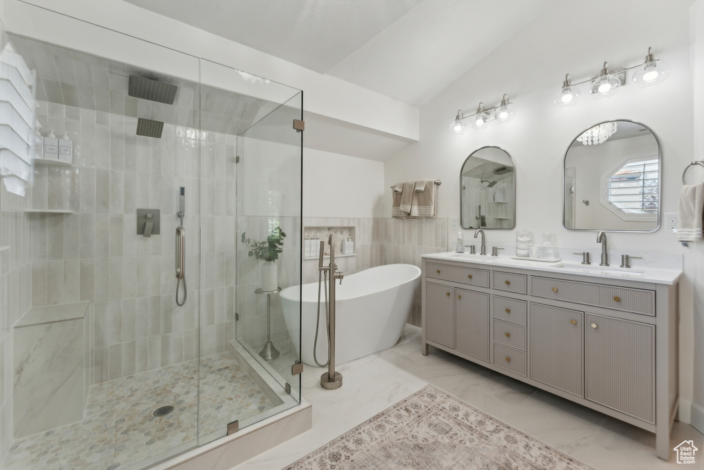 Full bathroom with a stall shower, double vanity, a freestanding tub, vaulted ceiling, and marble finish floors