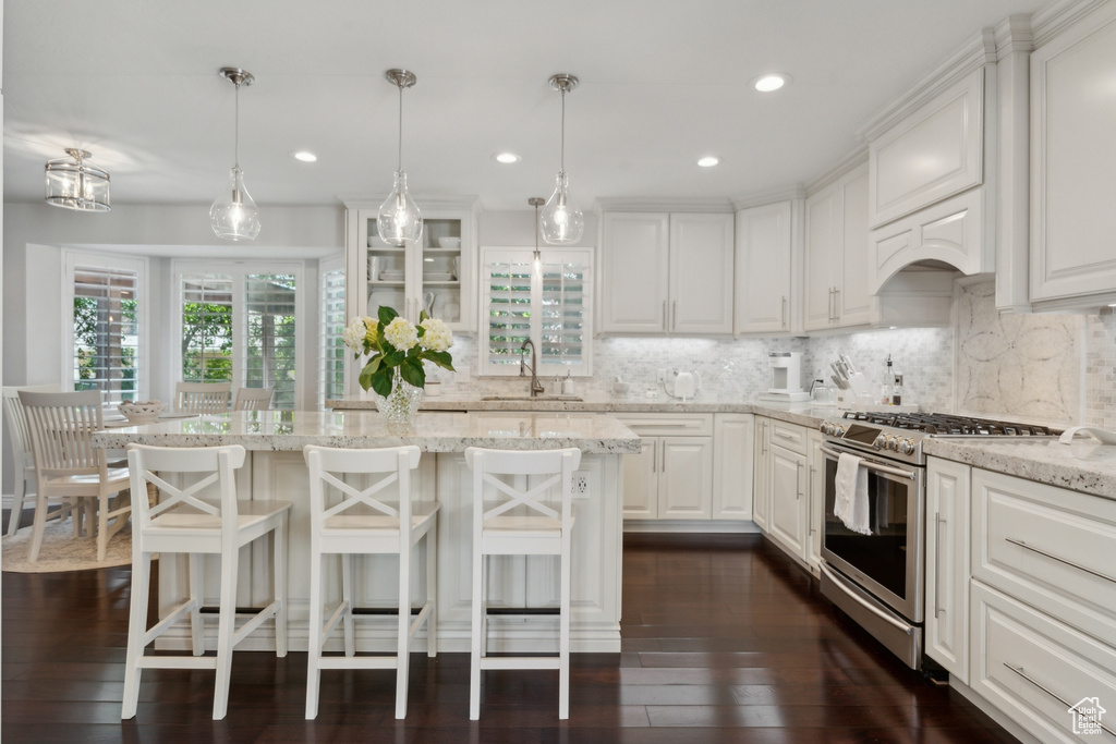 Kitchen with gas stove, a sink, decorative backsplash, white cabinetry, and recessed lighting