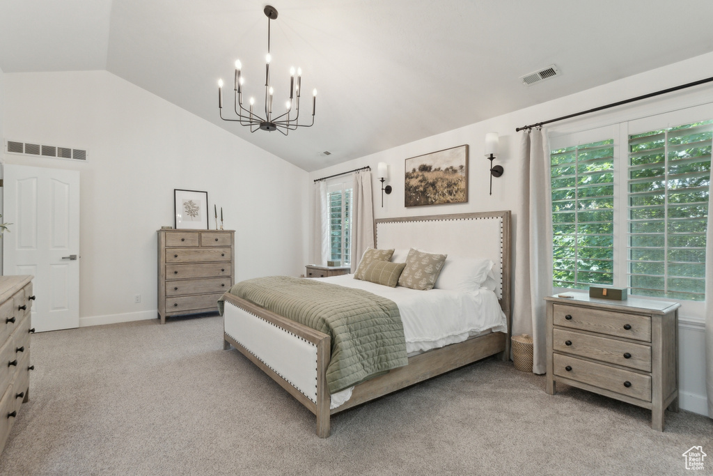 Bedroom with vaulted ceiling, a chandelier, light colored carpet, and baseboards