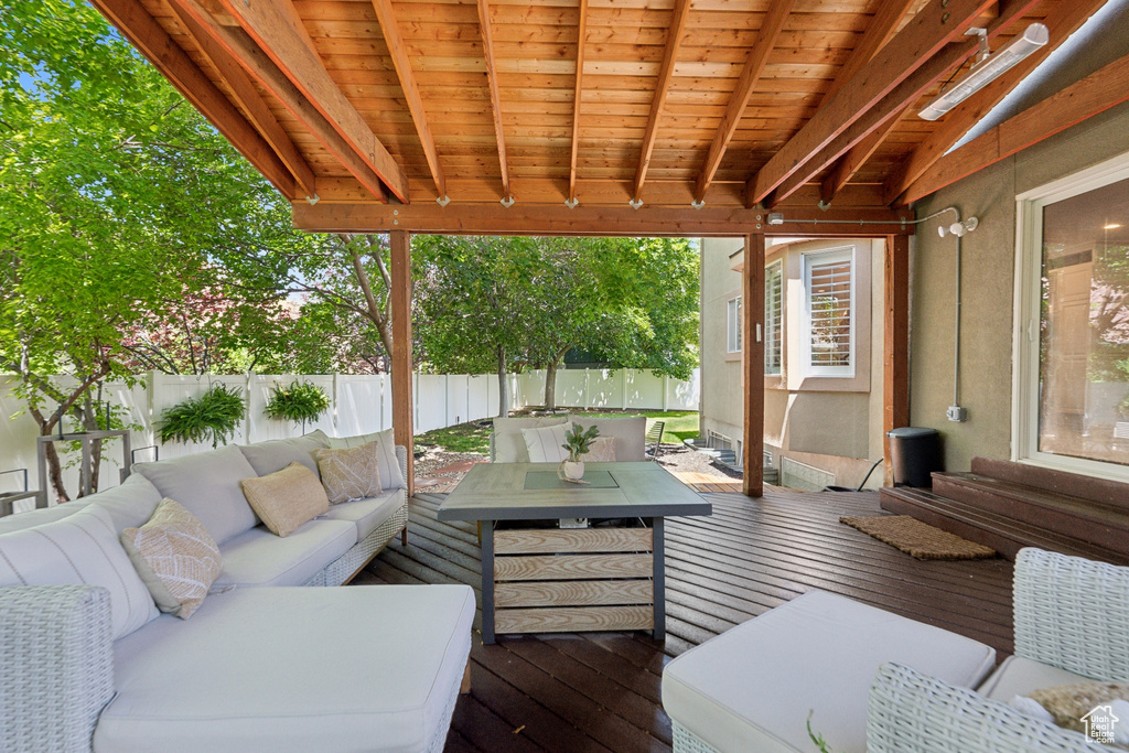 Wooden deck with an outdoor living space and a fenced backyard