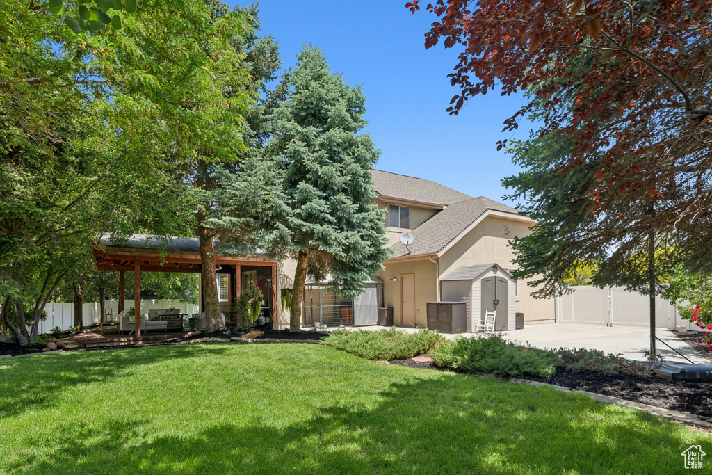 View of property hidden behind natural elements featuring a patio, stucco siding, and a shingled roof